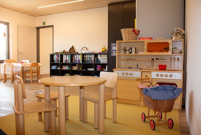 Spielecke mit Kinderküche, Puppenwagen und rundem Tisch